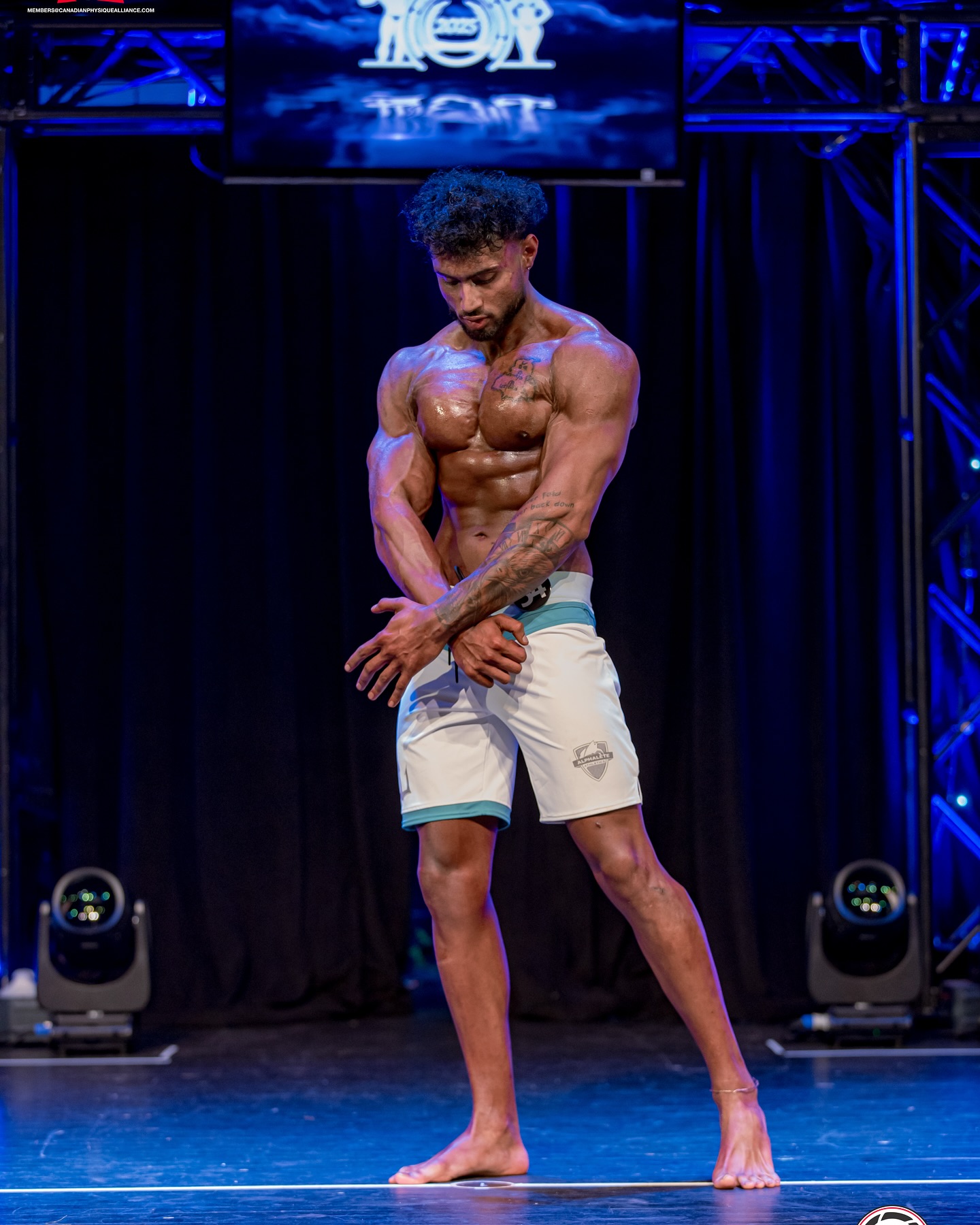 Mandip Singh competing on stage as a physique athlete